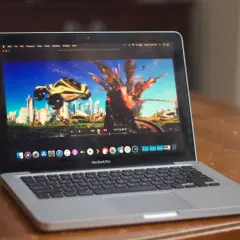 A MacBook Pro displays the "Speed Racer" trailer on the IINA player, showing a futuristic city and a car mid-explosion.