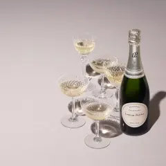 Laurent-Perrier Champagnerflasche mit gefüllten Gläsern. Die Dosage Champagner Bedeutung liegt in der perfekten Balance.