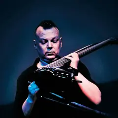 Kasper Toeplitz, z charakterystycznym irokezem, skupiony na grze na basie elektrycznym.