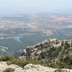 Vistas panorámicas de la sierra de Cazorla, Segura y Las Villas, con un embalse turquesa y campos cultivados al fondo.