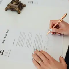 Kobieta podpisuje dokument "DIVORCE DECREE". To ważny pozew, który kończy pewien etap życia.
