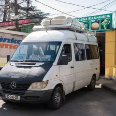 Biały bus z napisem "BORJOMI AKHALTSIKHE" na przedniej szybie, gotowy do podróży. To może być Twój sposób, jak dojechać z Kutaisi do Batumi, jeśli cel podróży jest inny.