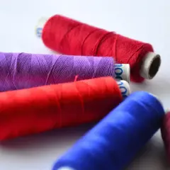 Kilka kolorowych nitek do szycia na białym tle.
