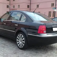 Svart Passat W8 parkerad på kullerstensgata framför en rosa byggnad.