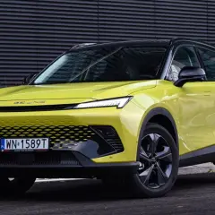 Jasnozielony BAIC 5 z czarnym dachem, nowoczesnym grillem i LED-owymi światłami, zaparkowany przed ciemną, falistą ścianą.