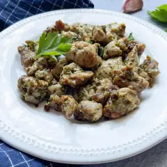 Deliciosas mollejas al ajillo, doradas y jugosas, servidas en un plato blanco con perejil fresco.