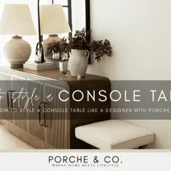 Learn how to style a console table with this designer guide. The image shows a beautifully styled console table with lamps, books, and a vase of flowers.