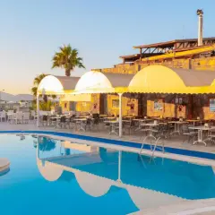 Basen i restauracja z żółtymi markizami w Sunpoint Hotel Bodrum. Idealne miejsce na relaks i posiłek.