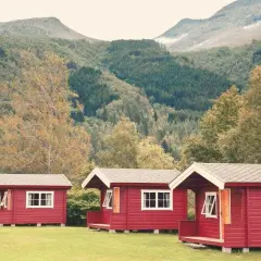 Czerwone domki kempingowe w malowniczej scenerii górskiej, idealne na camping w Norwegii.