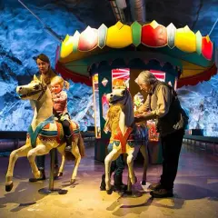 Familj njuter av en karusell i en grotta, en del av Stockholm Toy Museum.