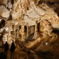 Odkrywanie najpiękniejszych jaskiń w Polsce. Dwie osoby podziwiają imponujące stalaktyty i stalagmity w oświetlonej grocie.