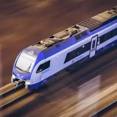 Niebiesko-biały pociąg PKP Stadler mknie po torach. Zastanawiasz się, ile kosztuje bilet ulgowy PKP?