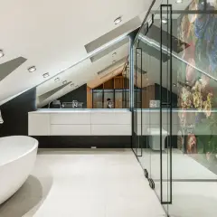 Nowoczesna łazienka z wolnostojącą wanną i prysznicem z mozaikową ścianą. Oświetlenie niskiego sufitu podkreśla architekturę wnętrza.