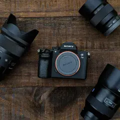 Aparat Sony Alpha 7 III z obiektywami na drewnianym tle.