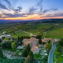 Tramonto mozzafiato sulla **chianti region**, con vigneti rigogliosi e un borgo toscano che si illumina sotto il cielo colorato.