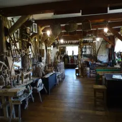 Wnętrze muzeum kultury bojkowskiej w Myczkowie. Widać tu liczne narzędzia, koło młyńskie, kosze i inne przedmioty codziennego użytku.