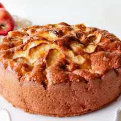 Bizcocho de manzana casero, dorado y jugoso, con trozos de manzana caramelizada en la superficie.