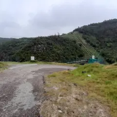 Camino de acceso a la fervenza da roca, con tuberías y vegetación en la ladera.