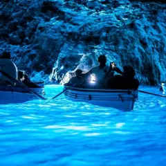 Barche a remi navigano nelle acque luminose della Grotta Azzurra, un luogo magico dove si trova questo spettacolo naturale.