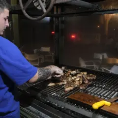 Joven cocinero prepara carnes a la parrilla en un restaurante, quizás en los charros cabo de gata.