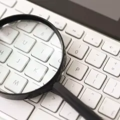 Lupa nad klawiaturą komputera symbolizuje jak przybliżyć ekran. Widoczne klawisze: N, M, J, K, P, U, Y, I, 0.