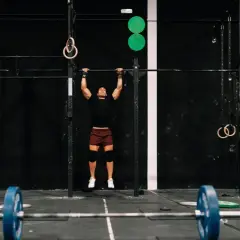 Mężczyzna wykonujący podciąganie na drążku w siłowni CrossFit.