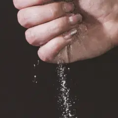 Une main saupoudre du sel, une expression culinaire qui sublime les saveurs.