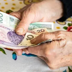 Dłonie liczą pieniądze. Zmagania z niepełnosprawnością sprzężoną utrudniają codzienne czynności, jak zarządzanie finansami.