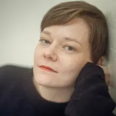 Johanna Frid lutar sig mot en vägg, med handen mot kinden.