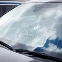 Parabrisas delantero de coche con una gran grieta en forma de telaraña, necesita un cambio.
