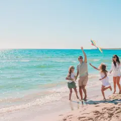 Rodzina puszcza latawiec na plaży. Idealne miejsce, gdzie nad morze z niemowlakiem, by cieszyć się słońcem i zabawą.