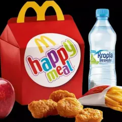 Czerwone pudełko z napisem "happy meal", obok jabłko, nuggetsy, frytki i butelka wody. Taka hepi mil cena to świetna opcja dla dzieci.