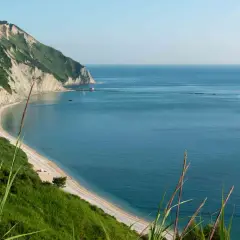 Vista panoramica della spiaggia di Mezzavalle, con scogliere verdi e mare azzurro. Le recensioni la descrivono come un paradiso.