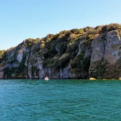 Un'emozionante visita all'isola Martana, con le sue scogliere imponenti e il mare turchese. Una piccola barca si avvicina alla costa rocciosa.