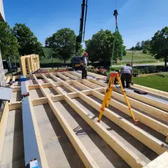 Construction d'une surélévation bois. Des ouvriers installent la structure en bois d'un étage supplémentaire, avec une grue en arrière-plan.