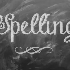 Het woord "Spelling" is met sierlijke letters op een krijtbord geschreven. Een decoratieve krul siert de onderkant.