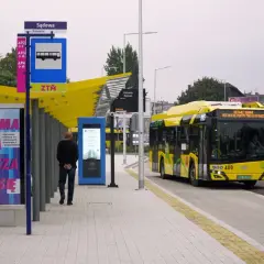 Dworzec autobusowy Katowice Sądowa. Żółty autobus elektryczny zatrzymuje się na przystanku. Rozkład jazdy widoczny na tablicy informacyjnej.