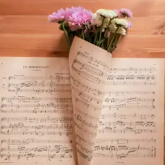 Un mazzo di fiori rosa e bianchi adagiato su spartiti musicali. Le note sembrano le canzoni della mamma, piene di dolcezza.