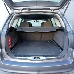 Pusta przestrzeń bagażowa Astry H kombi. Widoczna apteczka i roleta. Idealna do przewożenia bagażu, poznaj astra h kombi wymiary.