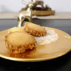 Goldene Platte mit drei Friesenkeksen, bestreut mit Zucker und gehackten Mandeln. Ein goldener Hirsch im Hintergrund. Das ist das original Friesenplätzchen Rezept.
