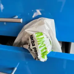 Biała reklamówka z zielonym napisem "Torba" wystaje z niebieskiej szuflady. Oto praktyczny sposób, jak przechowywać reklamówki.