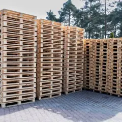 Stosy drewnianych palet czekają na załadunek. Zastanawiasz się, ile zmieści się palet na tirze?