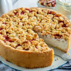 Ein köstlicher Rhabarberkuchen mit Schmand und knuspriger Streuselhaube. Rhabarberstücke sind unter den Streuseln versteckt.