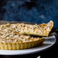 Ein Stück einer sensationellen Apfeltarte mit Mandelblättchen wird herausgehoben. Ein wahrer Genuss!