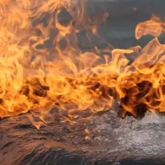 Flammen lodern über sprudelndem Wasser. Das Brandverhalten von CFL-S1-Materialien wird hier eindrucksvoll demonstriert.