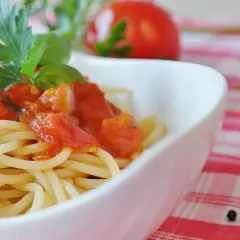 Eine Schüssel mit Spaghetti und einer herzhaften Tomatensoße, garniert mit frischem Basilikum und Petersilie.