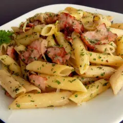 Pyszny makaron penne z kawałkami wędzonego boczku i posypany natką pietruszki. Idealny makaron na obiad.