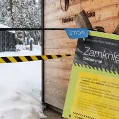 Tablica informacyjna "Zamknięty szlak" w Tatrach zimą, z taśmą ostrzegawczą.