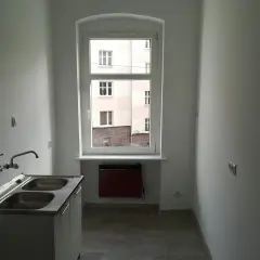 Nowe mieszkanie komunalne, gotowe do zamieszkania. Zastanawiasz się, ile wynosi czynsz za mieszkanie komunalne? Tutaj jest kuchnia z dwukomorowym zlewem i widokiem na podwórko.