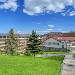 Górnicze sanatorium z panelami słonecznymi na dachu, otoczone zielenią. Miejsce odpoczynku dla każdego górnika.